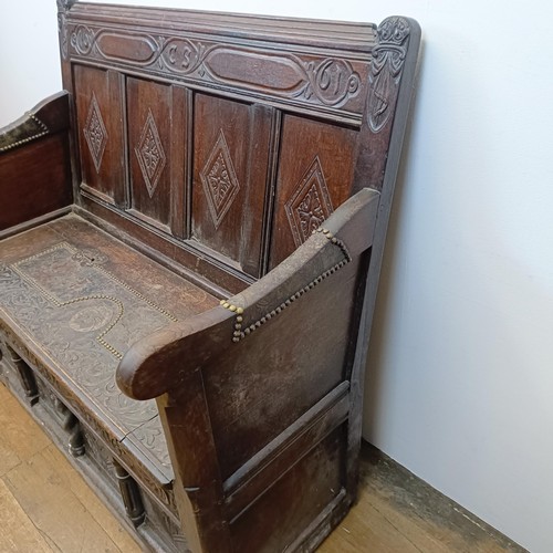 874 - A 17th century style carved oak settle, with a painted leather panel to the seat and arms, 130 cm wi... 