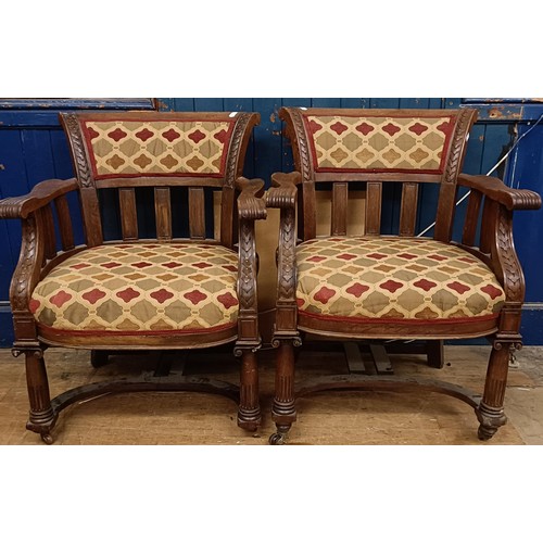 1695 - A pair of late Victorian carved oak armchairs, with padded backs and seats, on ionic column legs to ... 