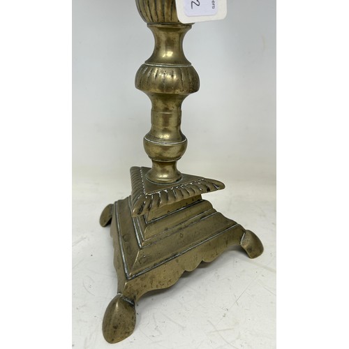 1364 - A pair of 17th century brass candlesticks, on triangular bases, 36 cm high