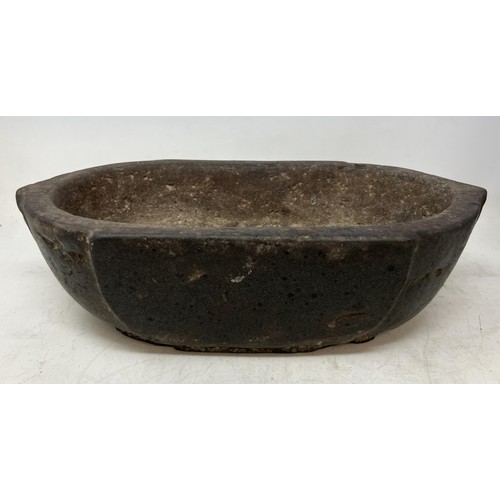 1334 - A carved stone bowl, of rounded rectangular form, 33 cm wide, and three marble spheres, approx. 10 c... 