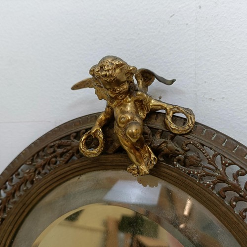 1425 - A wall mirror, the pierced brass frame surmounted by a cherub, 28 cm high, and a Sitzendorf style po... 