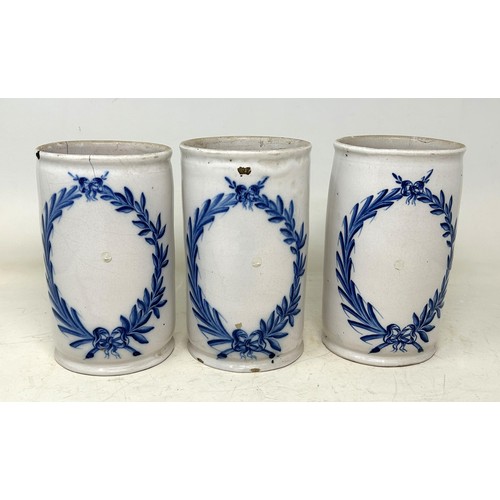 1336 - A set of three Delft pottery drug jars/cylindrical vases, decorated leaf garlands, in underglaze blu... 