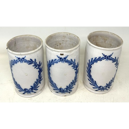 1336 - A set of three Delft pottery drug jars/cylindrical vases, decorated leaf garlands, in underglaze blu... 