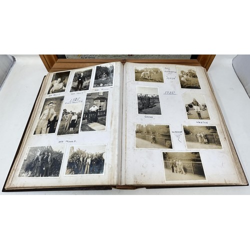 1383 - An early 20th century photograph album, with a carved wooden cover, contents of family portraits and... 