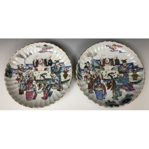 1621 - A pair of Chinese dishes, of lobed circular form, decorated figures around a table, in famille rose ... 