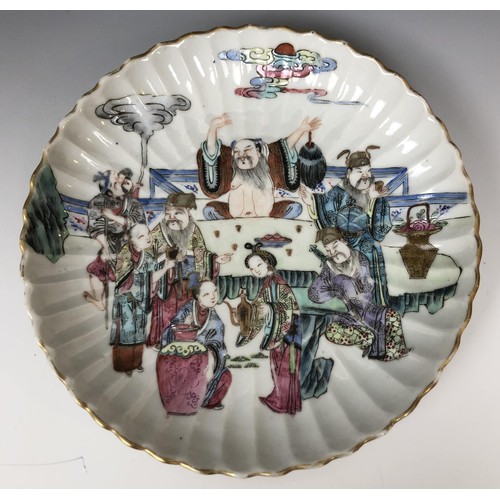 1621 - A pair of Chinese dishes, of lobed circular form, decorated figures around a table, in famille rose ... 