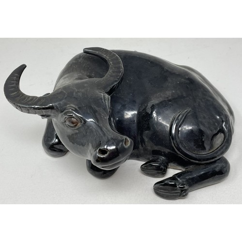 1508 - A Chinese pottery figure, of a recumbent water buffalo, on a hardwood stand, 17 cm high, and two Chi... 