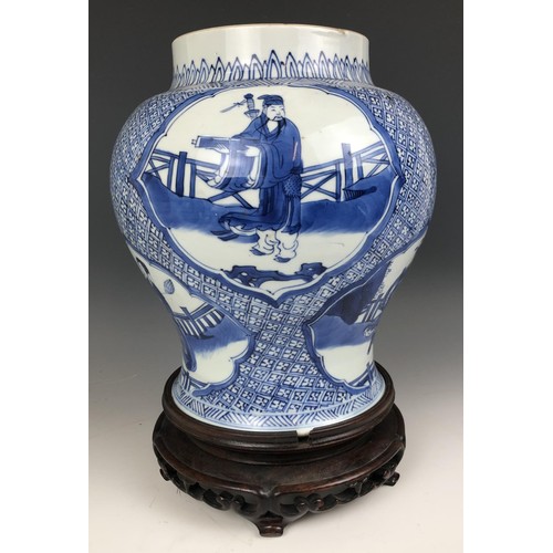 1569 - A Chinese blue and white vase, decorated figures, 20 cm high, on a carved wood stand