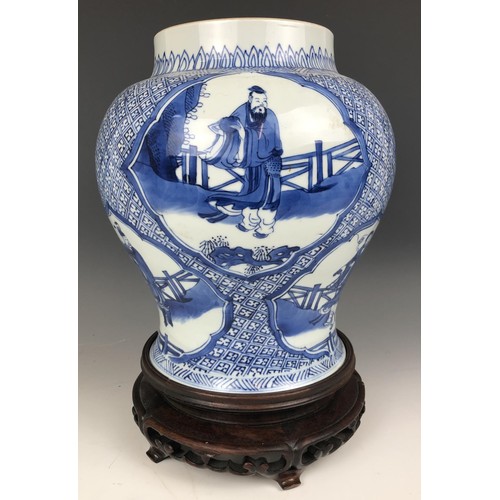 1569 - A Chinese blue and white vase, decorated figures, 20 cm high, on a carved wood stand