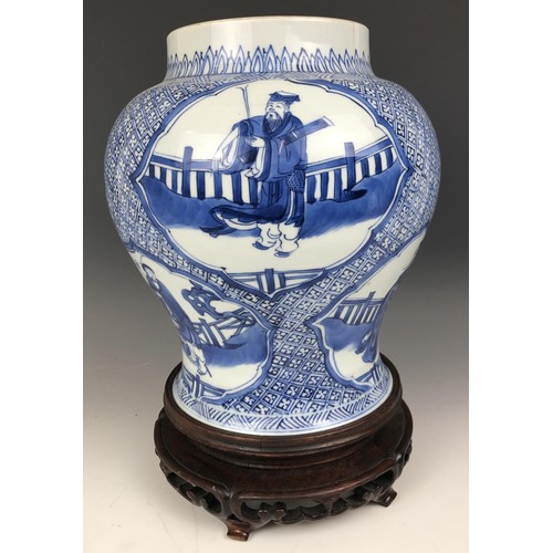 1569 - A Chinese blue and white vase, decorated figures, 20 cm high, on a carved wood stand