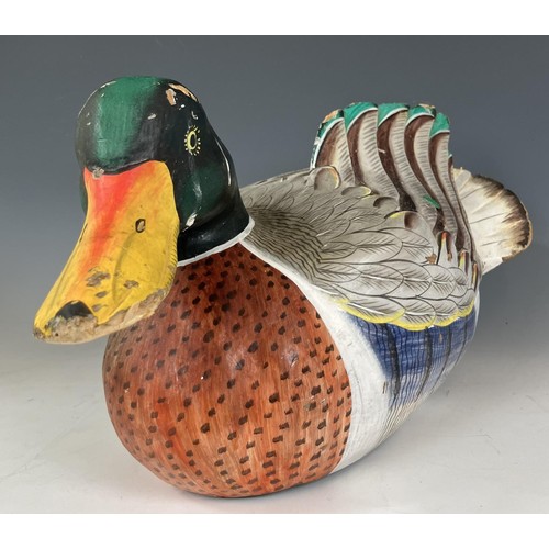 682 - A pottery figure of a duck, 30 cm wide, and a carved and painted figure of a duck, 51 cm wide (2)