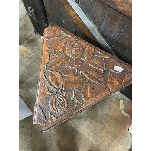 1951 - A carved walnut triangular table, with drop leaves, decorated leaves and pomegranates, 44 cm wide