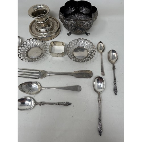 7 - An Indian silver coloured metal sugar bowl, assorted teaspoons, a napkin ring, a pair of pierced dis... 