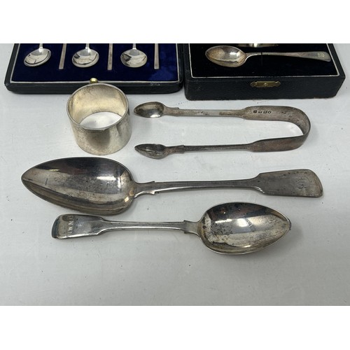 9 - A fiddle pattern spoon, another, a napkin ring, a pair of sugar tongs, an egg cup and spoon, cased, ... 