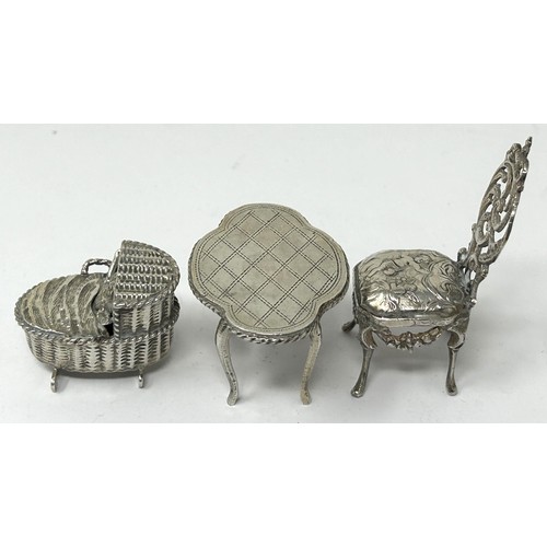 221 - A novelty silver ornament, of a baby in a bassinette, a miniature table and chairs (3)