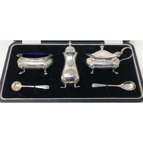 67 - A silver cruet, comprising mustard pot, salt, pepperpot, and two spoons, cased, a pair of napkin rin... 