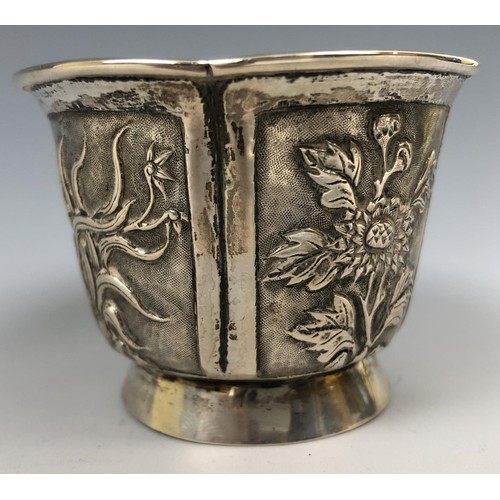 294 - A Chinese silver coloured metal beaker, embossed flowers and foliage, 5.5 cm high