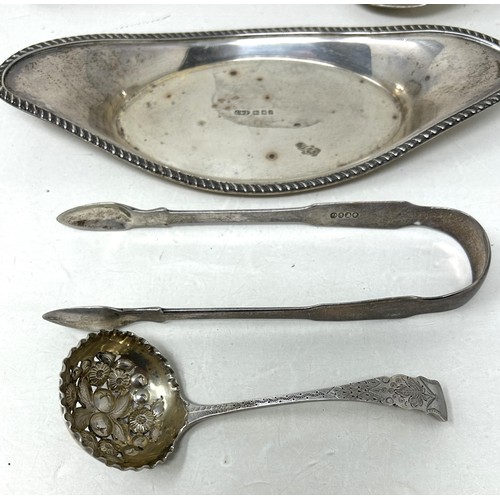 310 - A silver stand, a pair of sugar tongs, a ladle, and a fiddle pattern spoon, various dates and marks,... 