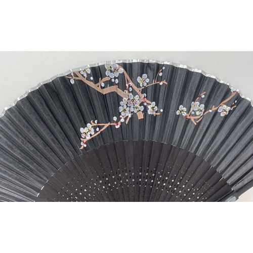 820 - An ebonised fan, the silk painted flowers, 25 cm, boxed, and five other fans (6)