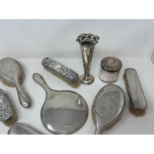 320 - A George V silver posy vase, a silver backed mirror, assorted brushes, and a glass box with a silver... 