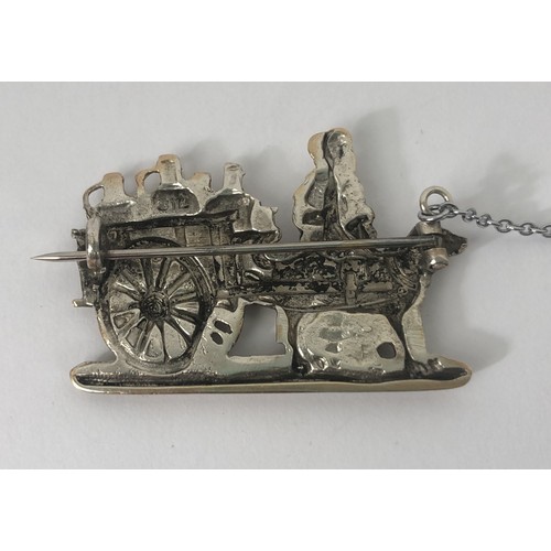 687 - A silver coloured metal brooch, in the form of a lady with a dog cart