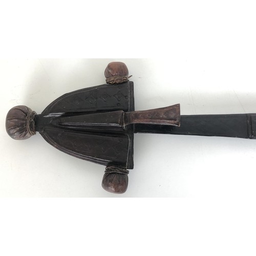 528 - An African Takouba style sword, the wooden handle inlaid with bone, in a leather mounted scabbard, f... 