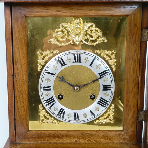 975 - A mantel clock, the brass dial with a silvered chapter ring, in an oak case, 56 cm high