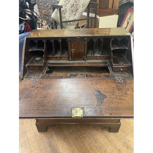 1059 - An 18th century oak bureau, the fall front revealing a fitted interior and a well, above two short a... 