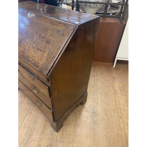 1059 - An 18th century oak bureau, the fall front revealing a fitted interior and a well, above two short a... 