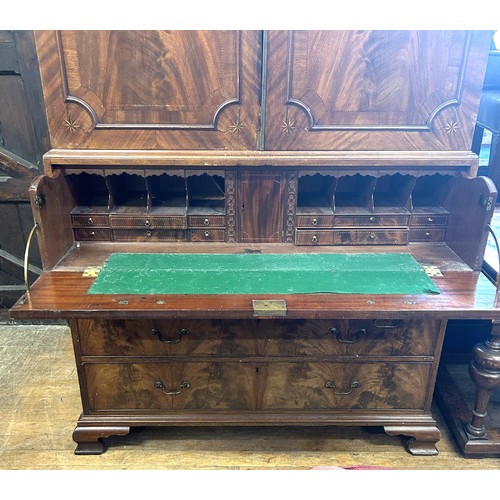 1062 - A 19th century inlaid mahogany linen press, the top having two cupboard doors, on a base with a secr... 