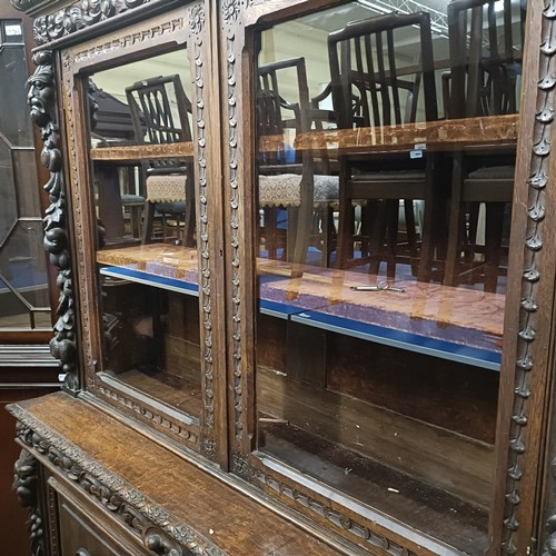 1080 - A late 19th century Anglo-Flemish carved oak bookcase, having a pair of glazed doors above a pair of... 