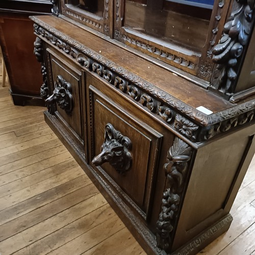 1080 - A late 19th century Anglo-Flemish carved oak bookcase, having a pair of glazed doors above a pair of... 