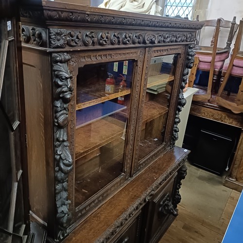 1080 - A late 19th century Anglo-Flemish carved oak bookcase, having a pair of glazed doors above a pair of... 