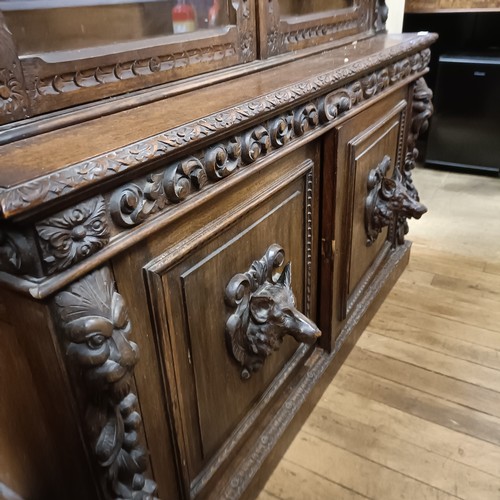 1080 - A late 19th century Anglo-Flemish carved oak bookcase, having a pair of glazed doors above a pair of... 