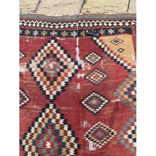 1128 - A red ground tribal rug, decorated four lozenge shaped medallions, 347 x 189 cm Provenance: On instr... 