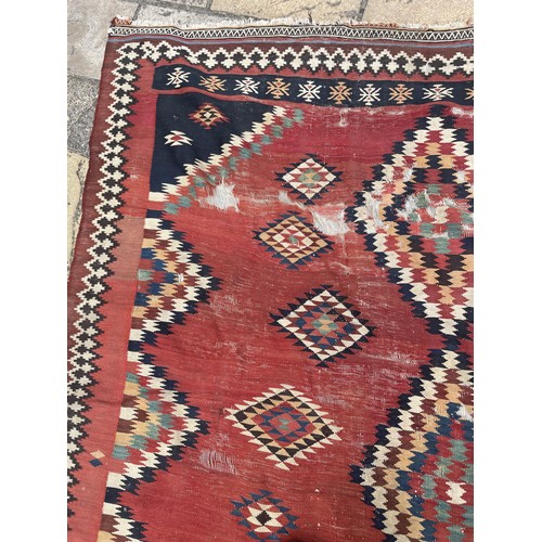 1128 - A red ground tribal rug, decorated four lozenge shaped medallions, 347 x 189 cm Provenance: On instr... 