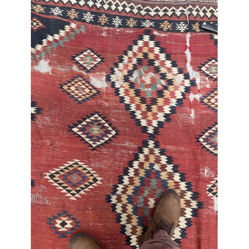 1128 - A red ground tribal rug, decorated four lozenge shaped medallions, 347 x 189 cm Provenance: On instr... 