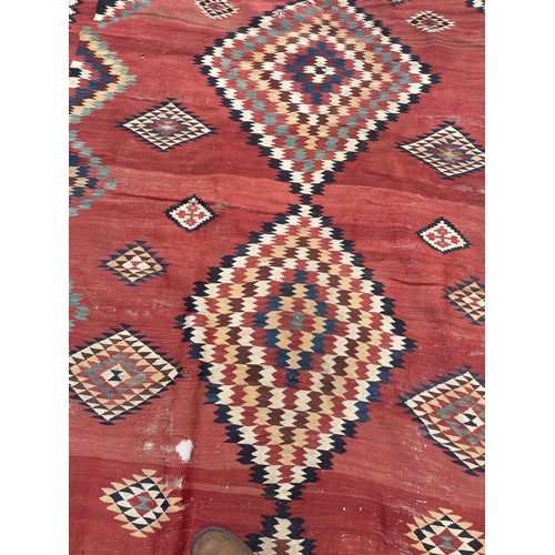 1128 - A red ground tribal rug, decorated four lozenge shaped medallions, 347 x 189 cm Provenance: On instr... 