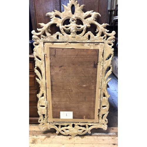 1130 - A wall mirror, with a carved wooden frame, in the rococo manner, 122 x 62 cm, Frost & Reed label... 