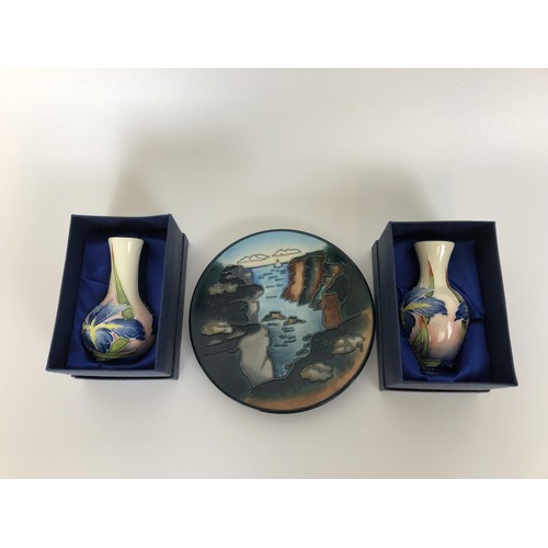 381 - A Moorcroft plate, decorated a landscape, 15 cm diameter, and a pair of Moorcroft style vases, boxed... 