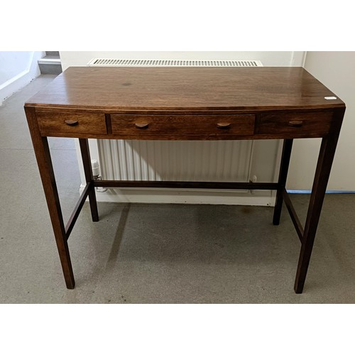 469 - A Cotswold School style walnut bow front table, having three freize drawers on tapering square legs ... 