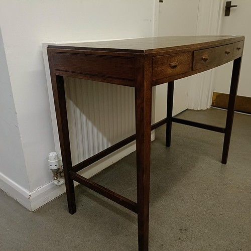 469 - A Cotswold School style walnut bow front table, having three freize drawers on tapering square legs ... 