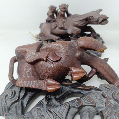 1325 - A pair of Chinese carved hardwood buffaloes, on stands, 24 cm wide