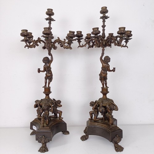 1309 - A pair of bronze figural five branch candelabra, on shaped bases and lion paw feet, 66 cm high