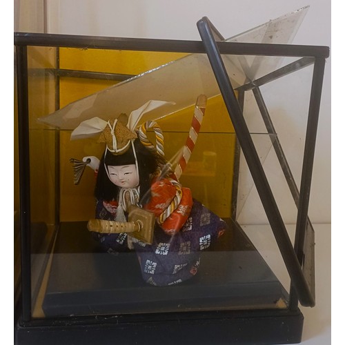 1226 - A Japanese doll, in traditional dress, in a glazed case, 54 cm high, and two others similar (3)