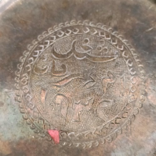 255 - An Iraqi silver coloured metal counter dish, with calligraphy to the centre, 7 cm diameter