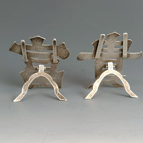 270 - A pair of Chinese silver coloured metal menu holders, in the form of characters, with engraved decor... 