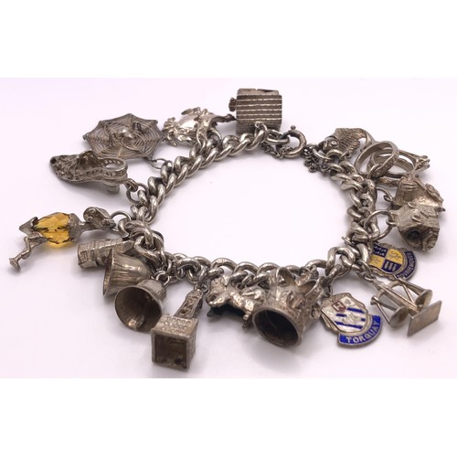 525 - A silver bracelet, with assorted silver and silver coloured metal charms...