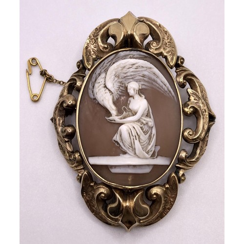 534 - A late 19th/early 20th century oval shell cameo brooch, decorated a lady, in a yellow metal scrolled... 