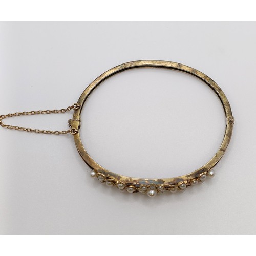 538 - A yellow metal and seed pearl floral bangle